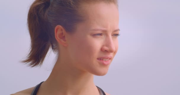 Close-up retrato de jovem bonito feminino jogger em sportswear olhando para a frente sendo determinado com céu azul no fundo ao ar livre — Vídeo de Stock