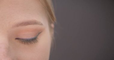 Genç güzel beyaz kadın yüz yakın çekim yarı yüz portre gri üzerinde izole arka plan ile gülümseyen ifade ile kamera bakıyor