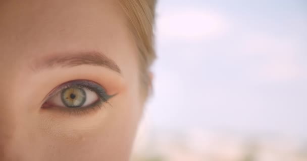Närbild Half Face porträtt av unga ganska kaukasiska kvinnliga ansikte med öga tittar på kameran är upphetsad utomhus — Stockvideo