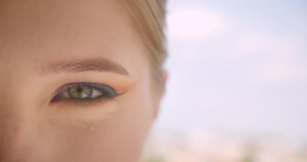 Closeup, napůl tvář portrét mladé ženy z bělošské tváře s očima, které se dívají na kameru s úsměvem v přírodě — Stock video