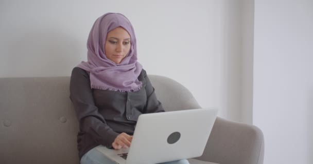 Retrato de cerca de la joven mujer de negocios musulmana en hijab usando el portátil en el interior del apartamento — Vídeos de Stock