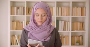 Tablet kullanarak ve kütüphanede kameraya yeşil renk ekran gösteren hijab genç güzel Müslüman kadın Closeup portre