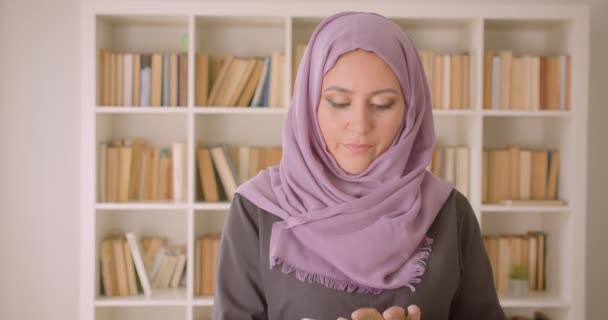 Retrato de primer plano de una joven mujer bastante musulmana en hijab usando la tableta y mostrando la pantalla de croma verde a la cámara en la biblioteca en interiores — Vídeos de Stock