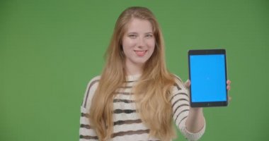 Tabletkullanarak genç güzel beyaz kadın Closeup çekim ve yeşil izole arka plan ile kameraya mavi renk anahtar ekranı gösteren