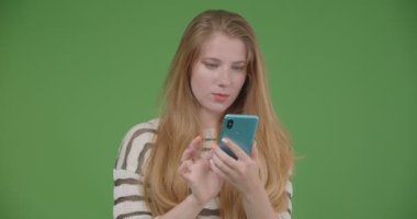 Telefonu kullanarak ve yeşil izole arka plan ile kameraya mavi ekran gösteren genç güzel beyaz kadın Closeup ateş