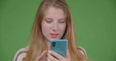 Telefonu kullanarak ve kameraya mavi ekran gösteren genç güzel beyaz kadın Closeup çekim mutlu gülümseyerek
