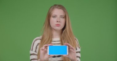 Cep telefonu kullanarak genç güzel kafkas kadın Closeup ateş ve izole arka plan ile yatay tutarak kamera mavi renk ekran gösteren