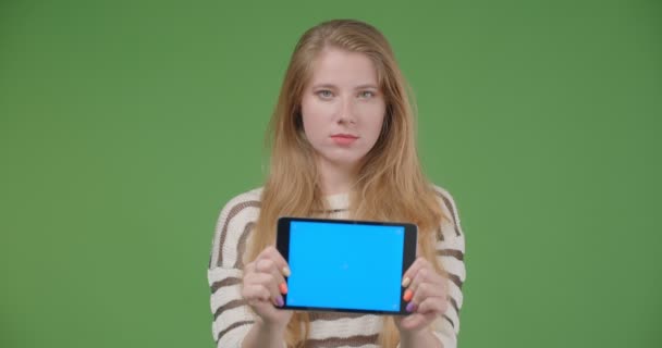 タブレットを使用して若いかわいい白人女性のクローズアップ撮影と孤立した背景で水平にそれを保持するカメラに青いクロマキー画面を示しています — ストック動画