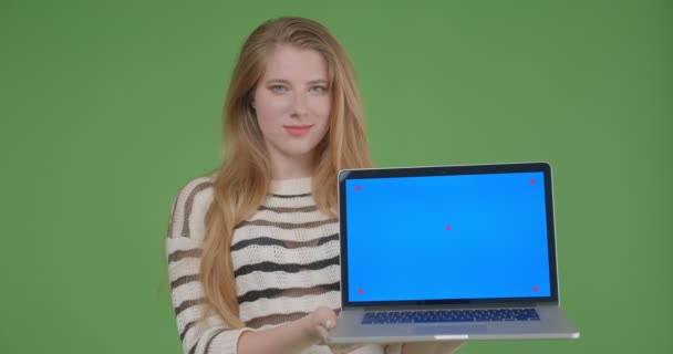 Nahaufnahme von jungen hübschen kaukasischen Frau hält den Laptop und zeigt blauen Chroma-Key-Bildschirm vor der Kamera mit isoliertem Hintergrund — Stockvideo