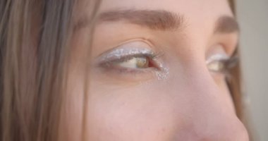 Genç güzel beyaz kadın yüz saç halkaları ve gözleri ile glitter makyaj ile closeup çekim kapalı beyaz odada kamera bakarak