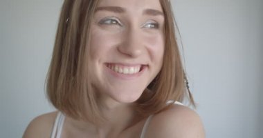 Saç halkaları ve glitter makyaj ile genç güzel beyaz kadın Closeup ateş mutlu beyaz oda kapalı yan bakarak gülüyor