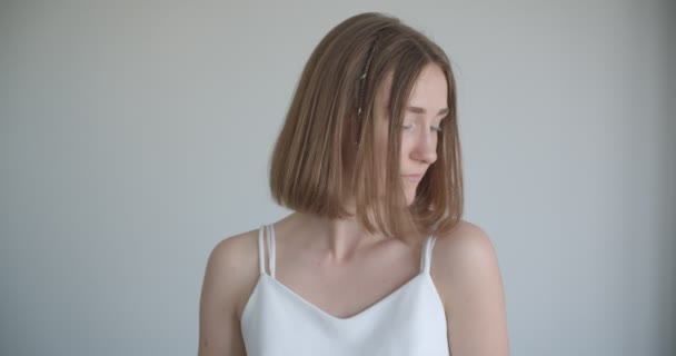 Närbild shoot av unga ganska kaukasiska kvinna med hår ringar tittar på kameran i vita rummet inomhus — Stockvideo