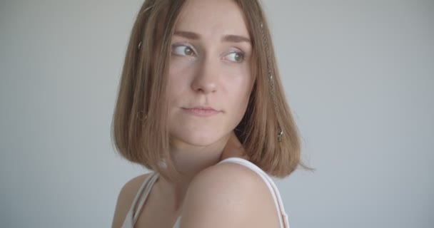Nahaufnahme Shooting der jungen hübschen kaukasischen Frau mit Haarringen und glitzerndem Make-up im weißen Raum drinnen — Stockvideo