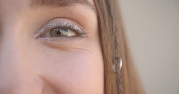 Primer plano media cara disparar de joven bastante caucásico hembra con anillos de pelo y maquillaje brillo sonriendo felizmente mirando a la cámara en la habitación blanca en el interior — Vídeo de stock