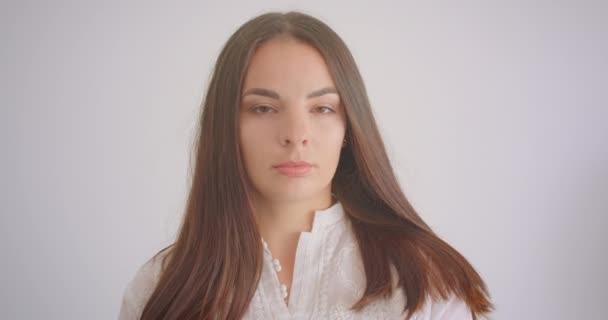 Крупный план портрета молодой белой студентки, смотрящей в камеру на белом фоне — стоковое видео