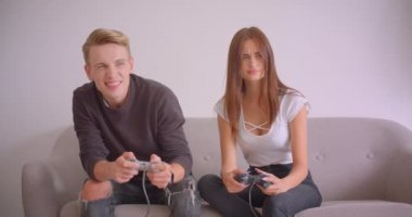 Dairede kapalı kanepede oturan birlikte video oyunları oynayan genç sevimli kafkas çift Closeup portre