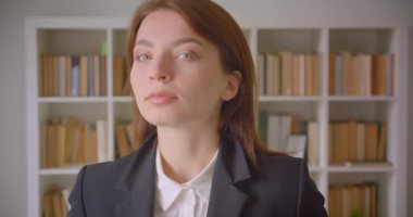 Kütüphanede kameraya bakan beyaz genç iş kadınının yakın çekim portresi