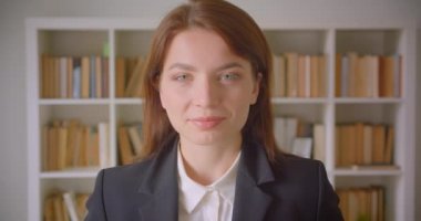 Genç kafkas iş kadınının kapalı kütüphanede mutlu bir şekilde gülümseyen kameraya bakan yakın çekim portresi