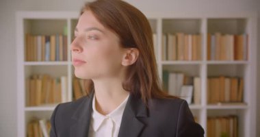 Arka planda kitaplıklar ile kütüphane kapalı neşeyle gülümseyen kameraya bakan genç kafkas iş kadını Closeup portre