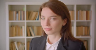 Kütüphanede gülümseyen kameraya bakan beyaz genç iş kadınının yakın çekim portresi