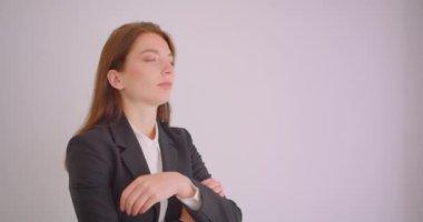 Beyaz ofiste kollarını göğüsüzerinden çapraz kameraya bakan genç beyaz iş kadını closeup portre