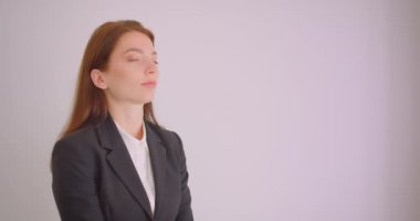 Beyaz ofiste kollarını göğüsüzerinden çapraz kameraya bakan genç beyaz başarılı iş kadını closeup portre