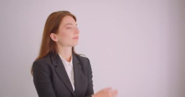 Beyaz ofiste kollarını göğüs üzerinden geçti mutlu bir şekilde gülümseyen kameraya bakan genç beyaz iş kadınının yakın çekim portresi