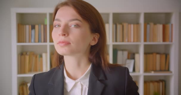 Primo piano ritratto di giovane donna d'affari caucasica che guarda la macchina fotografica sorridente allegramente in biblioteca al chiuso — Video Stock