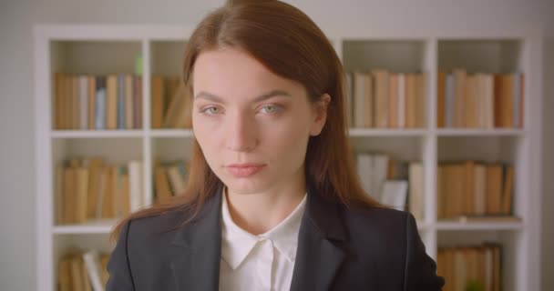 Крупный план портрета молодой уверенной кавказской предпринимательницы, смотрящей в библиотеку на камеру — стоковое видео