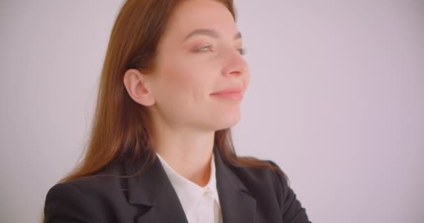 Retrato de close-up de jovem mulher de negócios caucasiana olhando para a câmera sorrindo alegremente com os braços cruzados sobre o peito no escritório branco — Vídeo de Stock