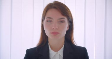 Beyaz ofiste güvenle kapalı kamera bakarak genç başarılı iş kadını Closeup portre