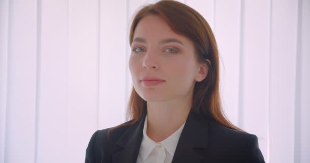Retrato de primer plano de la joven empresaria exitosa mirando a la cámara sonriendo felizmente de pie en el interior de la oficina blanca — Vídeo de stock