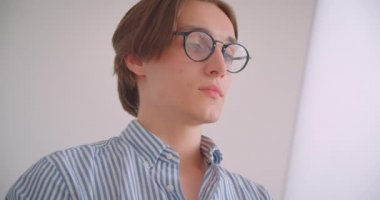 Dizüstü bilgisayar üzerinde çalışan genç yakışıklı beyaz işadamının kapalı koltukta mutlu bir şekilde otururken kameraya bakan yakın çekim portresi