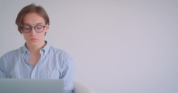 Genç çekici kafkas işadamının kapalı koltukta oturan kameraya bakan dizüstü bilgisayarı kullanarak yakın çekim portresi — Stok video