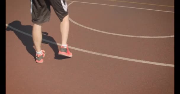 Close-up portret van jonge knappe Kaukasische mannelijke basketbalspeler gooien een bal in de hoepel op het veld buiten — Stockvideo