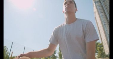 Parkta sahada potaya top atan genç atletik beyaz erkek basketbolcu yakın çekim portresi