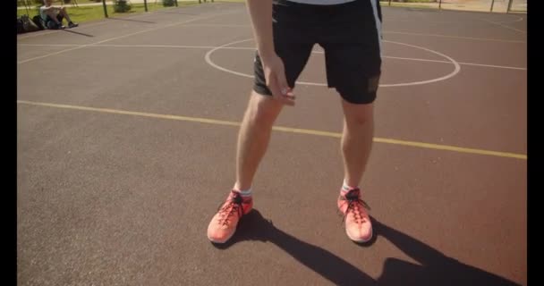 Retrato de primer plano de un joven y atractivo jugador de baloncesto caucásico lanzando una pelota en el aro en la cancha con paisajes urbanos en el fondo — Vídeo de stock