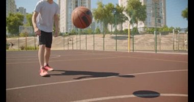 Genç çekici beyaz erkek basketbolcu arka planda binalar ile kortta pota topu atma Closeup portre