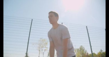 Genç beyaz erkek basketbolcu arka planda köprü ile açık sahada pota bir top atma Closeup portre