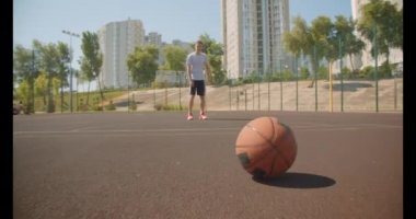 Genç aktif kafkas erkek basketbolcu arka planda kentsel binalar ile sahada pota topu atma Closeup portre