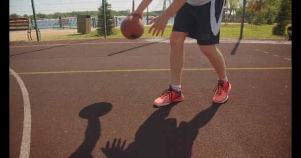 Nahaufnahme Porträt eines jungen sportlichen kaukasischen männlichen Basketballspielers, der auf dem Platz im Park einen Ball in den Korb wirft — Stockvideo