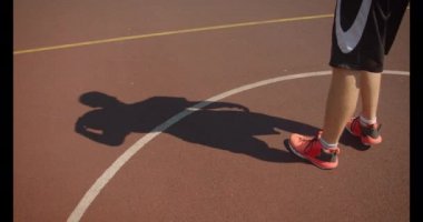 Erkek basketbolcu closeup portre başarıyla arka planda köprü ile zemin açık havada gölge ile sahada pota bir top atma