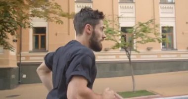 Binaların yanında şehir dışında sokakta duran yetişkin kafkas sportif erkek koşucu closeup portre