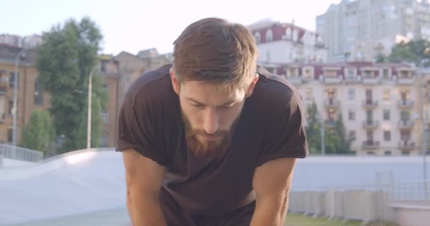 Close-up portret van volwassen Kaukasische atletische mannelijke jogger voorbereiden om te rennen op het stadion in de stedelijke stad buitenshuis — Stockvideo