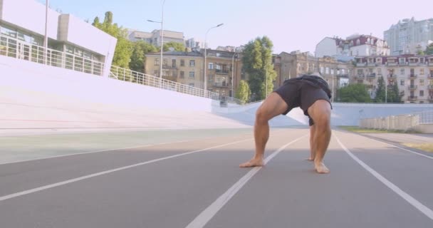 Крупный план портрета взрослого кавказского спортивного бегуна, выполняющего упражнения на потоке животных на стадионе в городском дворе — стоковое видео