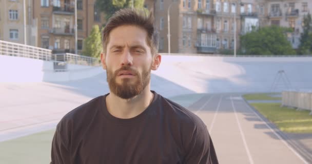 Closeup retrato de adulto caucasiano atleta masculino desportivo olhando para a câmera de pé no estádio na cidade urbana ao ar livre — Vídeo de Stock