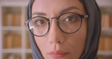 Gözlük ve başörtüsü genç Müslüman kadın yüz closeup portre kütüphane kapalı kamera bakarak