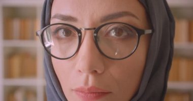 Gözlük ve başörtüsü genç Arap kadın yüz closeup portre kütüphane kapalı kamera bakarak