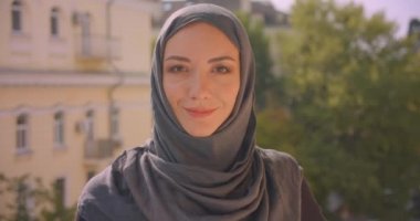 Arka planda manzara ile evin balkonunda duran kamera bakarak hijab genç çekici Müslüman kadının Closeup portre