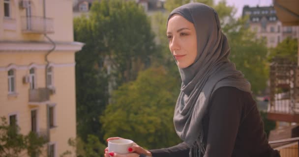 Primo piano ritratto di giovane donna musulmana attraente in hijab guardando il paesaggio in piedi sul balcone della casa — Video Stock